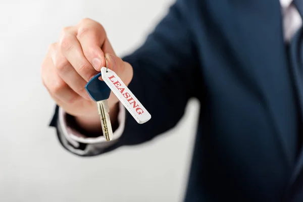 Vue recadrée de l'homme d'affaires tenant la clé avec leasing lettrage isolé sur blanc — Photo de stock