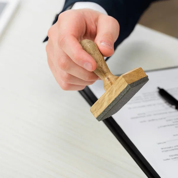 Vue recadrée de l'agent immobilier tenant le timbre près du presse-papiers sur le bureau, concept de location — Photo de stock