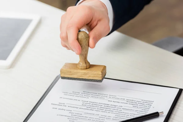 Vue recadrée de l'agent immobilier tenant le timbre près du presse-papiers avec document sur la table, concept de location — Photo de stock