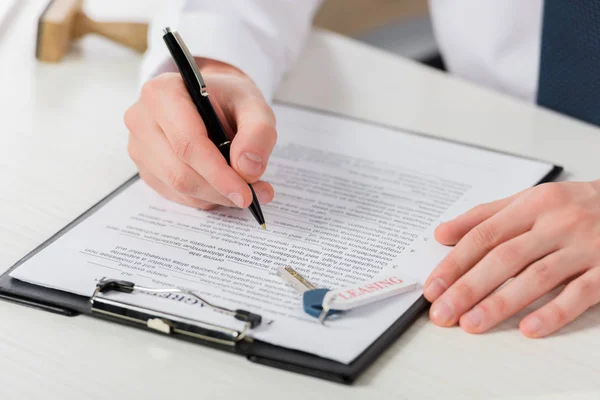 Cropped view of businessman holding pen near clipboard with document and key with leasing lettering — Stock Photo