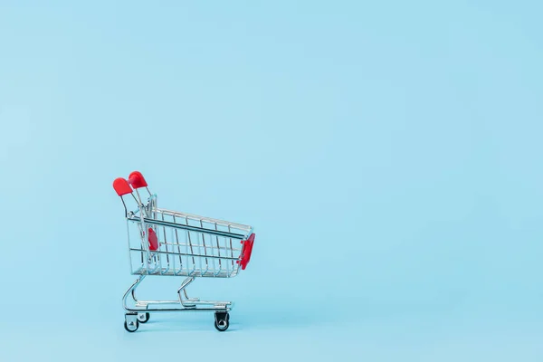 Carrinho de compras de brinquedo vazio em azul com espaço de cópia, conceito de locação — Fotografia de Stock