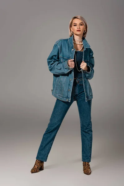 Jolie femme en jean et veste en jean regardant la caméra sur fond gris — Photo de stock