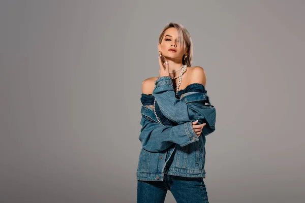 Attractive woman in denim jacket looking at camera isolated on grey — Stock Photo