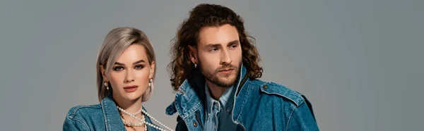 Panoramic shot of stylish man and woman in denim jackets isolated on grey — Stock Photo