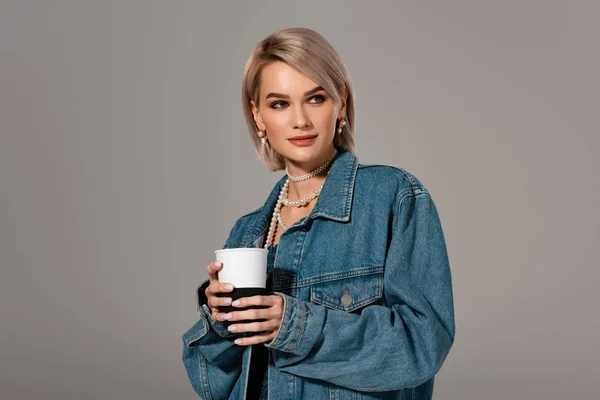 Attractive woman in denim jacket holding insulated mug isolated on grey — Stock Photo