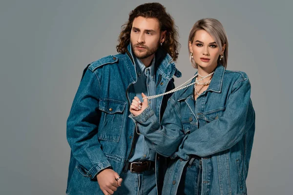 Стильный мужчина и женщина в джинсовой куртке изолированы на сером — стоковое фото