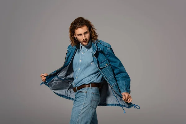 Handsome and stylish man in denim jacket and jeans looking away isolated on grey — Stock Photo