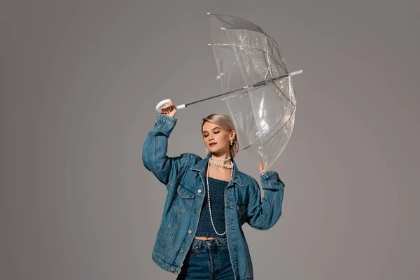 Mulher atraente em casaco de ganga segurando guarda-chuva isolado em cinza — Fotografia de Stock