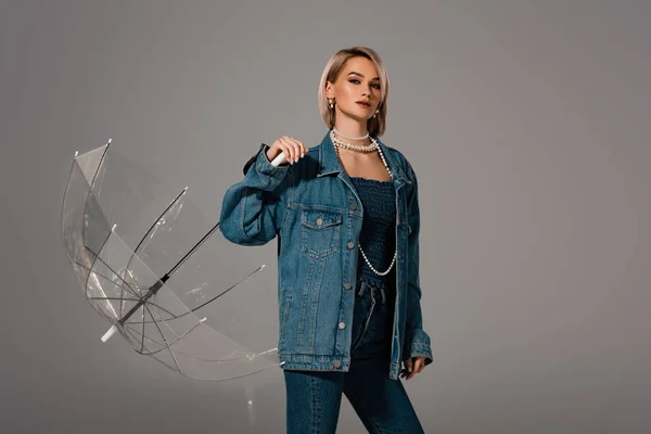 Attraktive Frau in Jeansjacke und Jeans, Regenschirm isoliert auf grau — Stockfoto