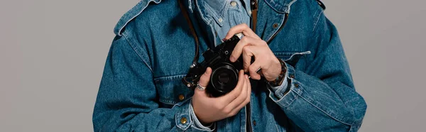 Panoramic shot of man in denim jacket holding digital camera isolated on grey — Stock Photo