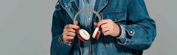 Panoramaaufnahme eines stilvollen Mannes in Jeansjacke mit Kopfhörern isoliert auf grau — Stockfoto