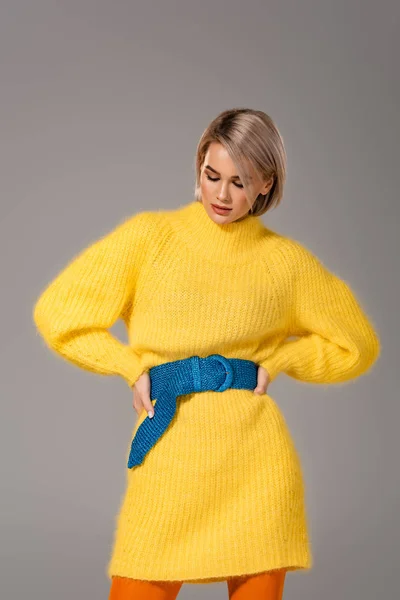 Jolie femme en robe jaune avec les mains sur les hanches isolées sur gris — Photo de stock