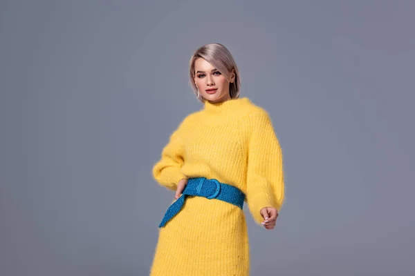 Attractive woman in yellow dress with hand on hip looking at camera isolated on grey — Stock Photo