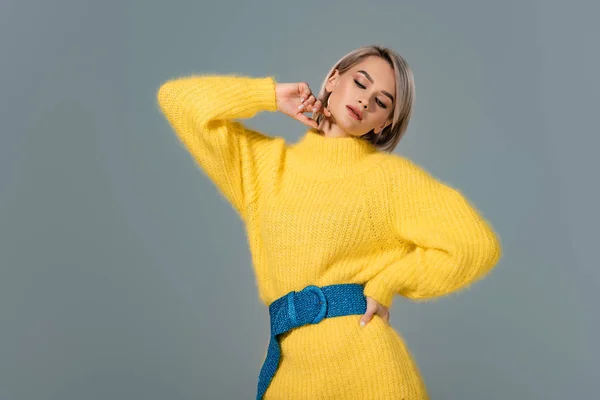 Atractiva mujer en vestido amarillo con la mano en la cadera aislada en gris - foto de stock