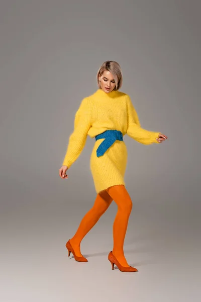 Mulher atraente em vestido amarelo andando sobre fundo cinza — Fotografia de Stock
