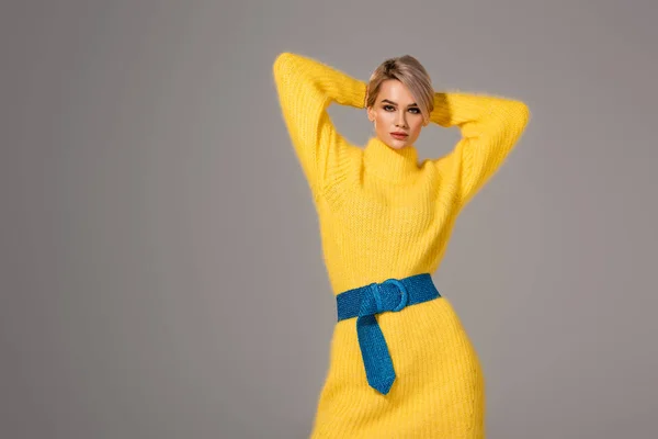 Atractiva mujer en vestido amarillo mirando a la cámara aislada en gris - foto de stock