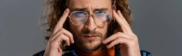 Панорамный снимок красивого мужчины в очках, смотрящего на камеру, изолированную на сером — стоковое фото
