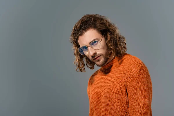 Handsome man in orange sweater looking at camera isolated on grey — Stock Photo