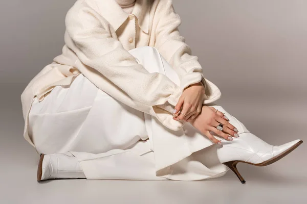 Обрезанный вид женщины в белом халате и брюках на сером фоне — стоковое фото