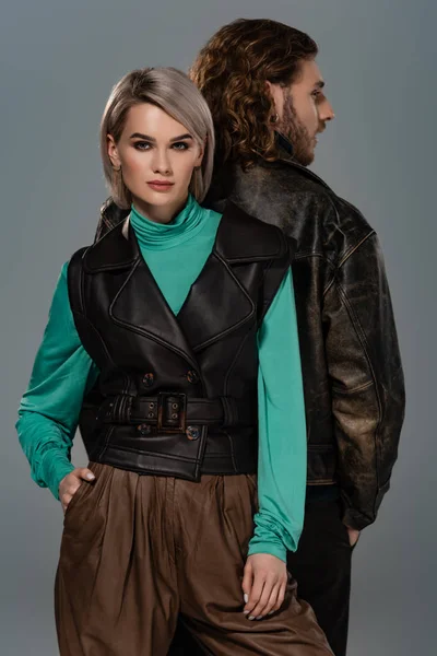 Mujer atractiva en chaleco y hombre en chaqueta de cuero aislado en gris - foto de stock