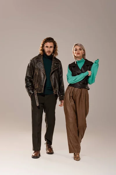 Frau in Weste und Mann in Lederjacke gehen auf grauem Hintergrund — Stockfoto
