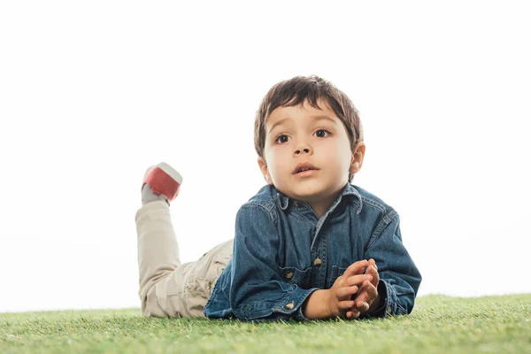 Niedlicher Junge, der wegschaut und isoliert auf weißem Gras liegt — Stockfoto