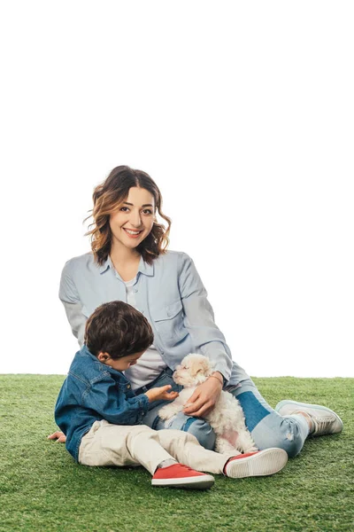 Sorridente madre guardando la macchina fotografica e il figlio accarezzando cucciolo Havanese isolato su bianco — Foto stock