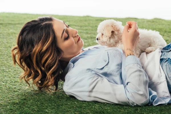 Mulher deitada na grama e olhando para filhote de cachorro Havanese isolado no branco — Fotografia de Stock