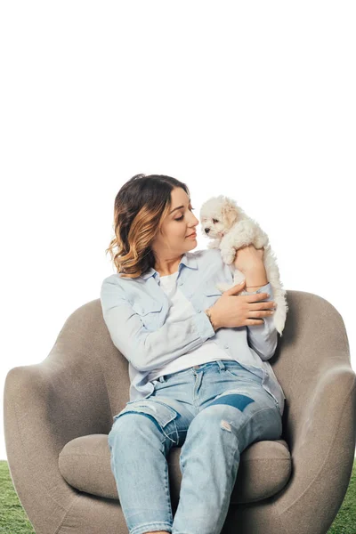 Smiling woman holding Havanese puppy and sitting on armchair isolated on white — Stock Photo