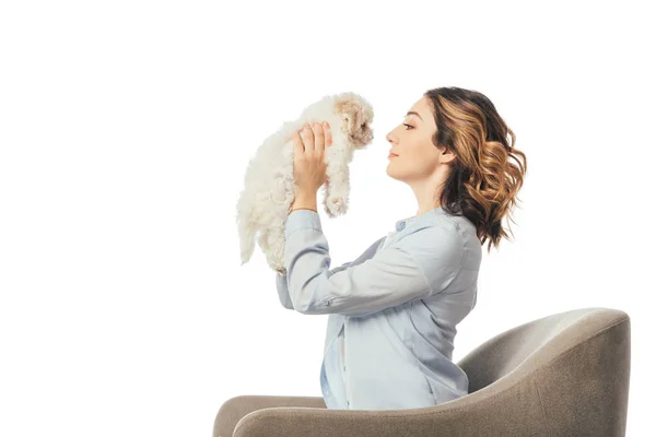 Side view of woman holding Havanese puppy and sitting on armchair isolated on white — Stock Photo
