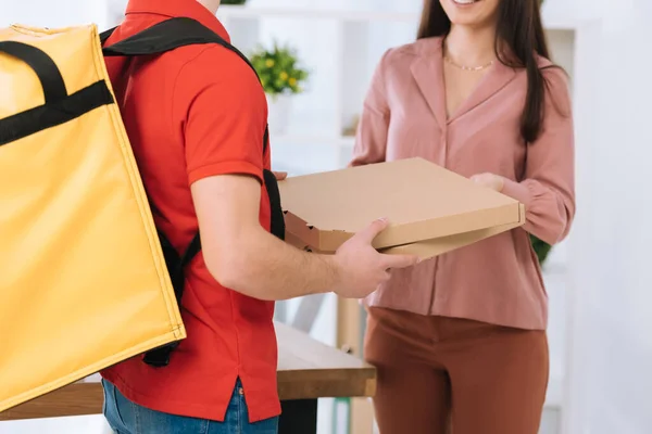 Vista recortada de mensajero con mochila termo dando cajas de pizza a mujer de negocios - foto de stock