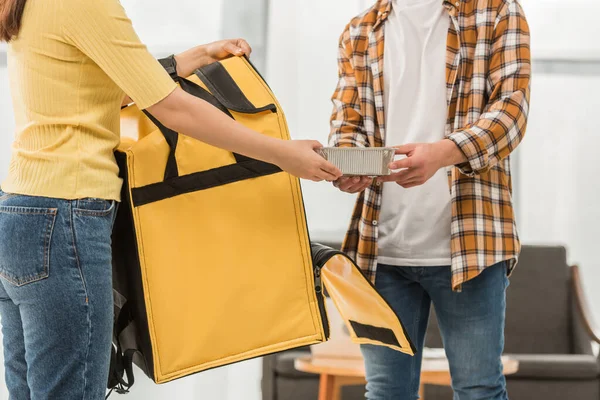 Ausgeschnittene Ansicht des Kuriers mit Thermosack, der dem Mann Lebensmittelbehälter gibt — Stockfoto