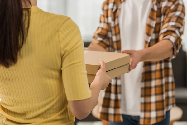Vista cortada do correio dando pizza em caixas para o homem — Fotografia de Stock