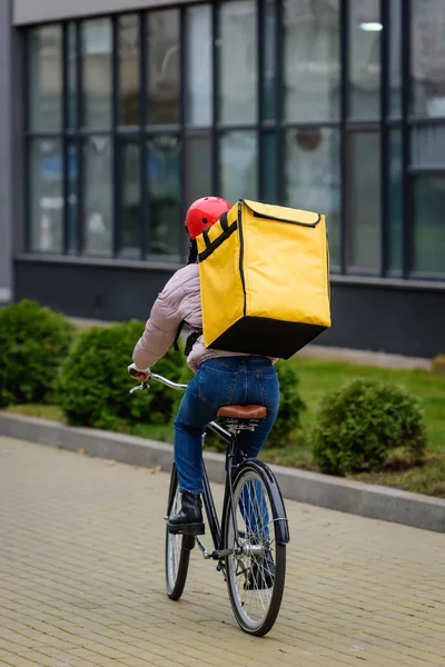 Back view of courier with thermo backpack riding bicycle on urban street — Stock Photo