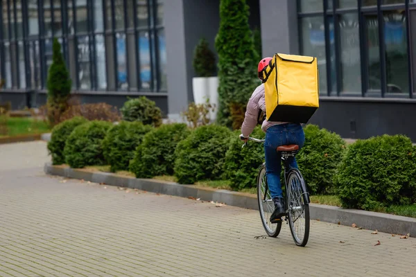 Visão traseira do correio com mochila térmica andar de bicicleta na rua urbana — Fotografia de Stock