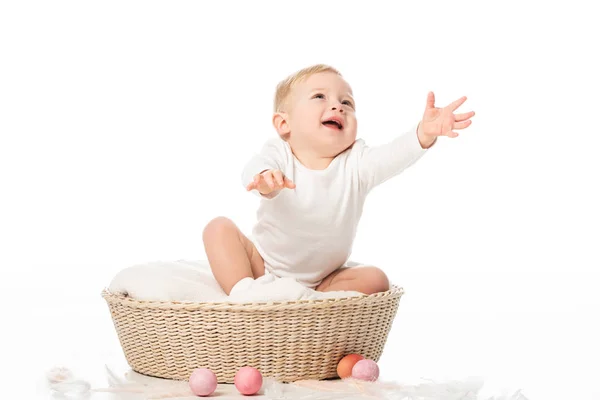 Criança bonito com as mãos estendidas e boca aberta sentado em cesta no fundo branco — Fotografia de Stock