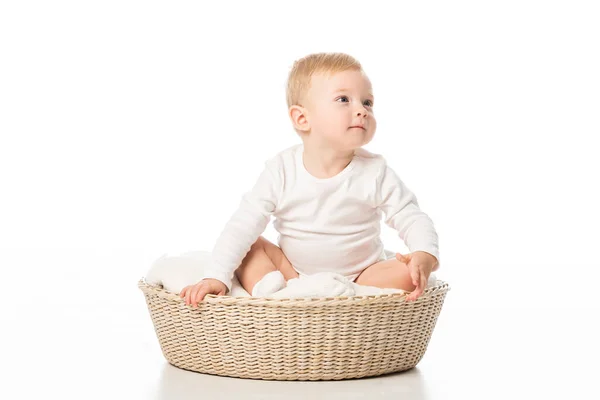 Carino bambino guardando lontano e seduto su una coperta nel cestino su sfondo bianco — Foto stock