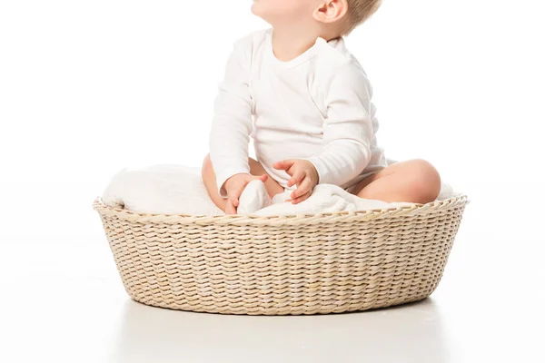 Vue recadrée de mignon enfant levant les yeux et assis sur la couverture dans le panier sur fond blanc — Photo de stock