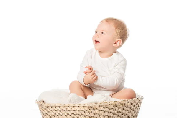 Niedliches Kind, das aufblickt und lacht, auf einer Decke im Korb auf weißem Hintergrund sitzend — Stockfoto