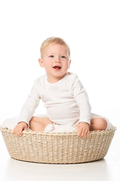 Милий хлопчик з відкритим ротом сидить на ковдрі в кошику на білому тлі — стокове фото