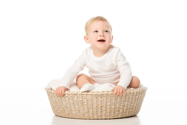 Rapaz bonito com boca aberta segurando cesta enquanto sentado dentro no fundo branco — Fotografia de Stock