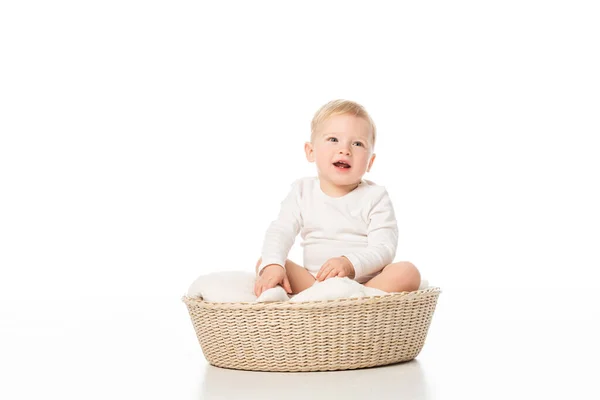 Garçon mignon avec la bouche ouverte assis sur la couverture dans le panier sur fond blanc — Photo de stock