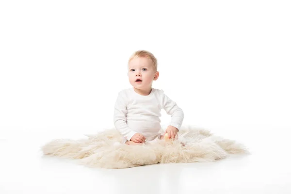 Cute kid with open mouth sitting on fur on white background — Stock Photo