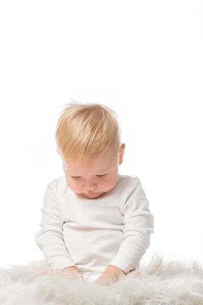 Cute child with lowered head sitting on fur isolated on white — Stock Photo