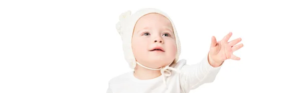 Cute kid wearing baby bonnet, looking up with outstretched hand isolated on white, panoramic shot — Stock Photo