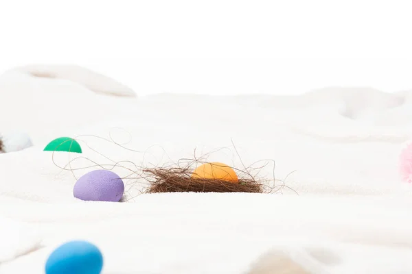 Enfoque selectivo del nido con yema y coloridos huevos de Pascua sobre manta blanca aislada sobre blanco - foto de stock
