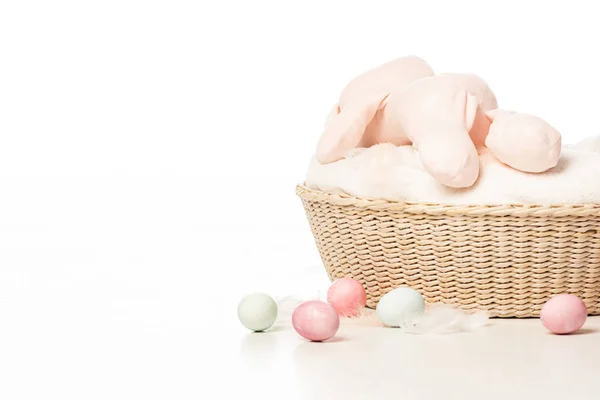 Coniglietto in cima alla coperta nel cestino accanto alle uova di Pasqua su sfondo bianco — Foto stock