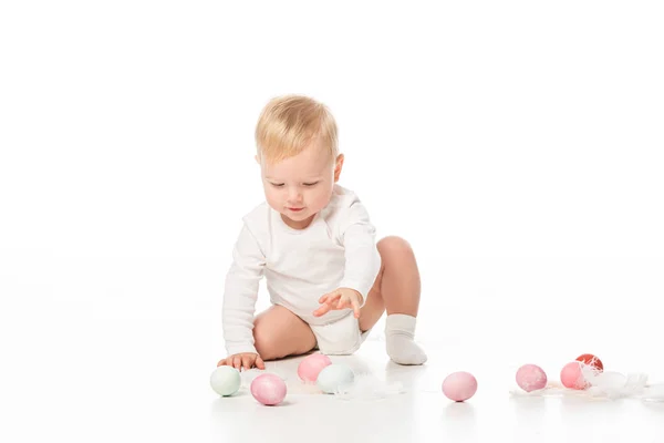 Lindo niño extendiendo la mano a los huevos de Pascua sobre fondo blanco - foto de stock