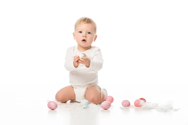Bambino con la bocca aperta, tenendo l'uovo di Pasqua e guardando la fotocamera su sfondo bianco — Foto stock