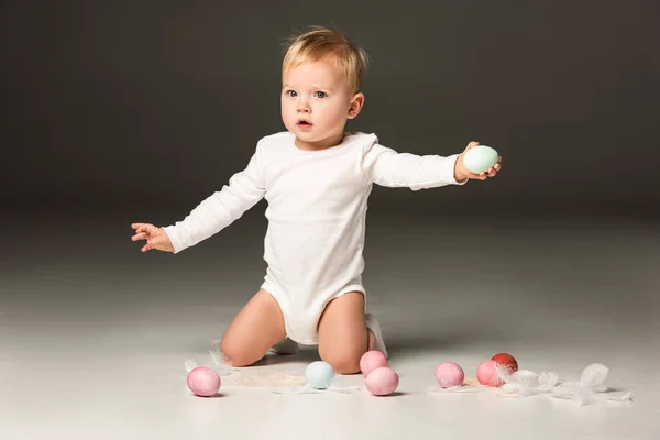 Lindo niño extendiendo las manos, sosteniendo huevos de Pascua sobre fondo negro - foto de stock